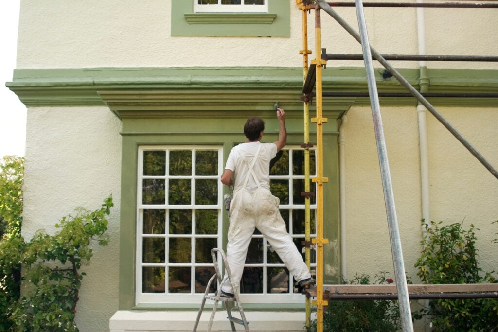 A painter at work, standing on a ladder, carefully painting a surface