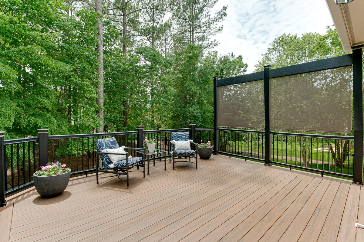a new deck with black metal railings shown with a wooded backyard