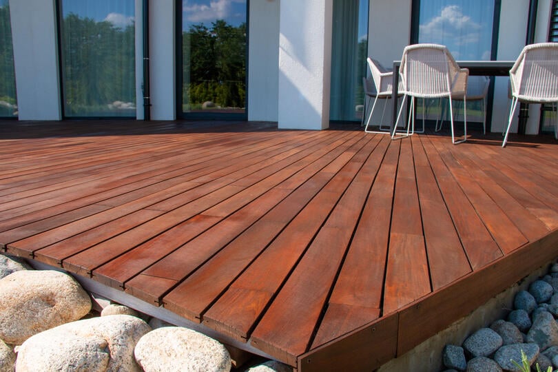 deck styles-dark wood deck off a house with stones around the edge