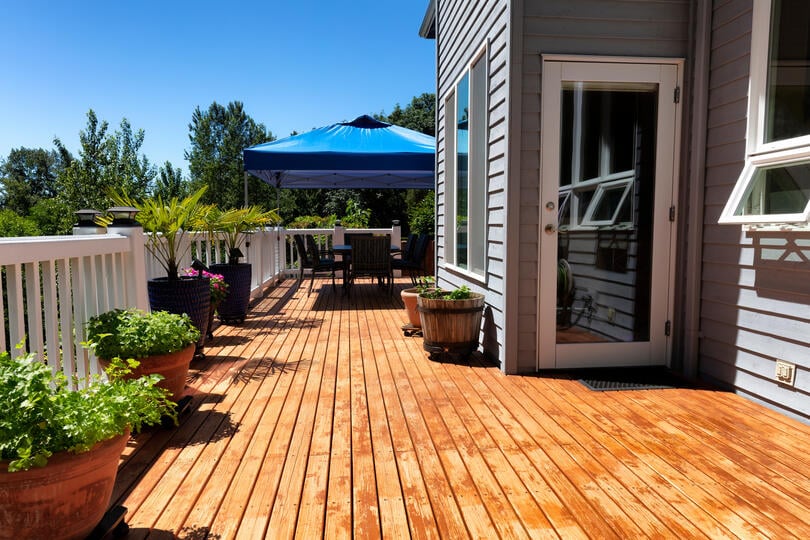 deck styles-wood deck with white railing off a home with potted plants and outdoor furniture