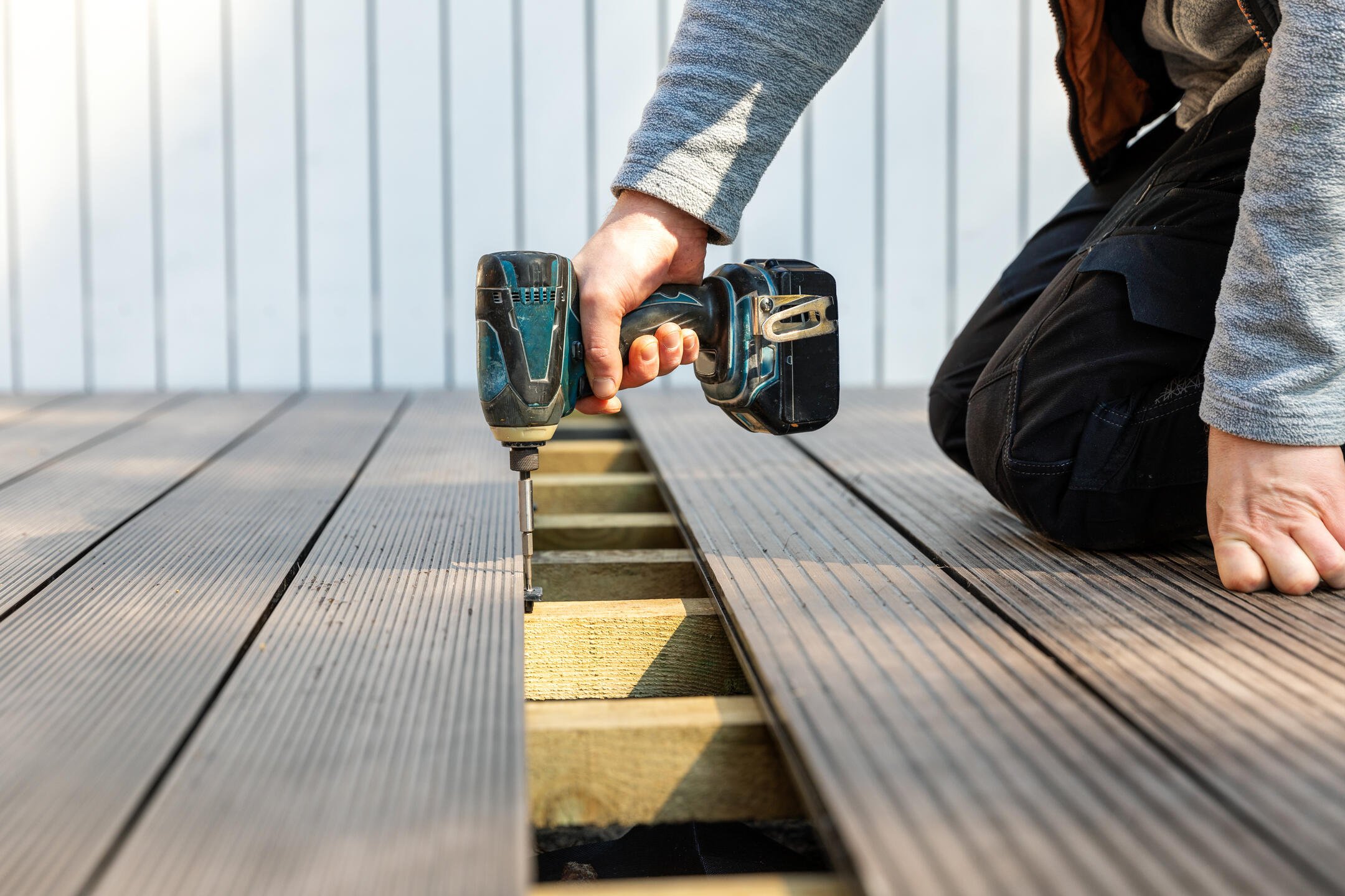 parts of a deck-person using power drill to install decking materials