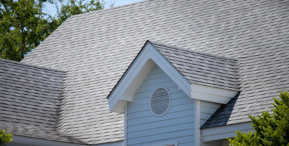 asphalt roof repair-light gray shingle roof on a white sided house