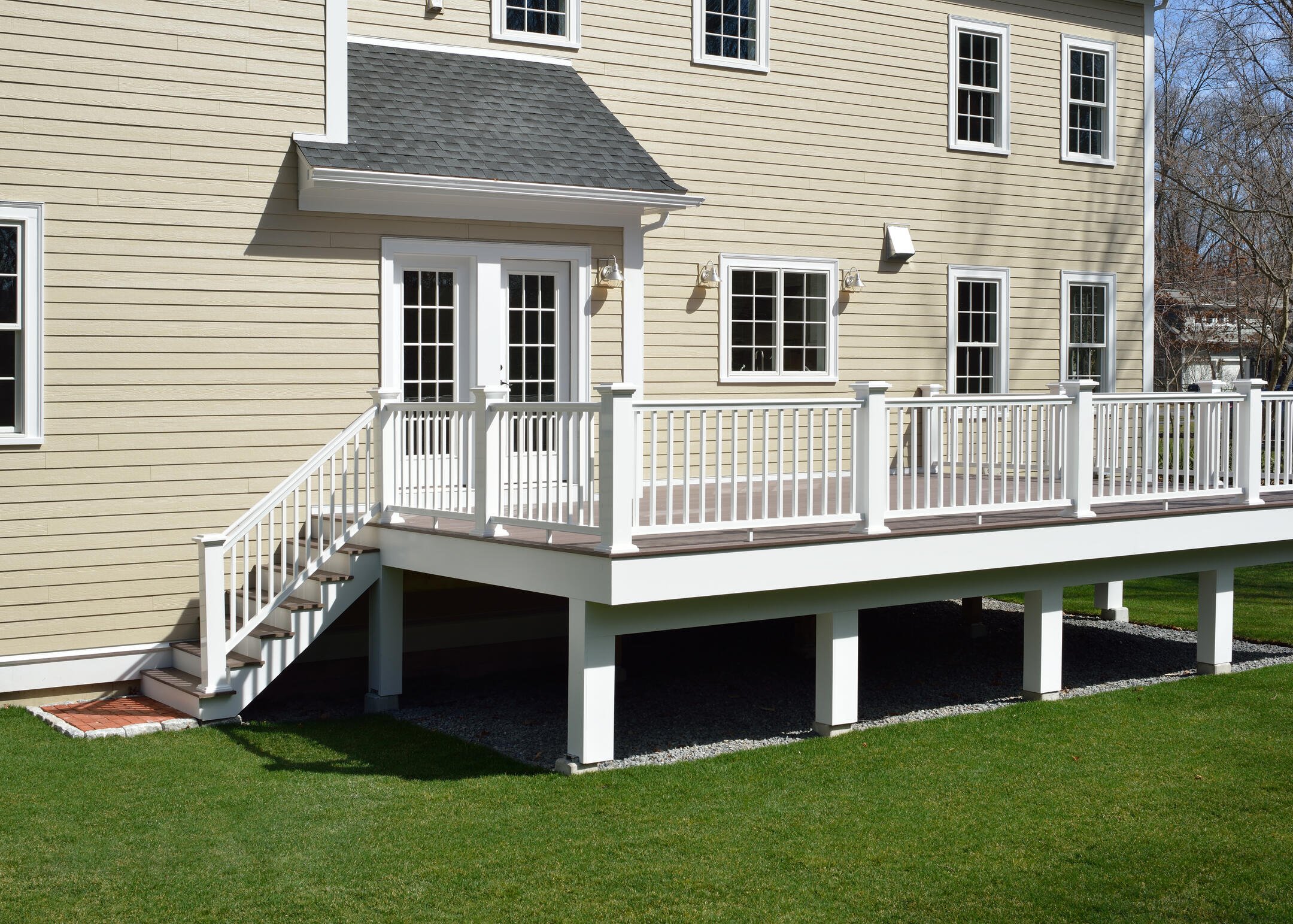 best decking material-cream colored house with a dark stained wood deck and white railing