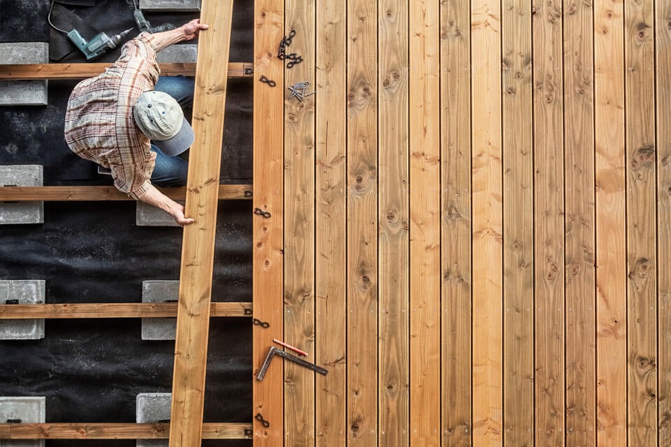 how to build a deck-arial view of a man laying deck boards on a foundation