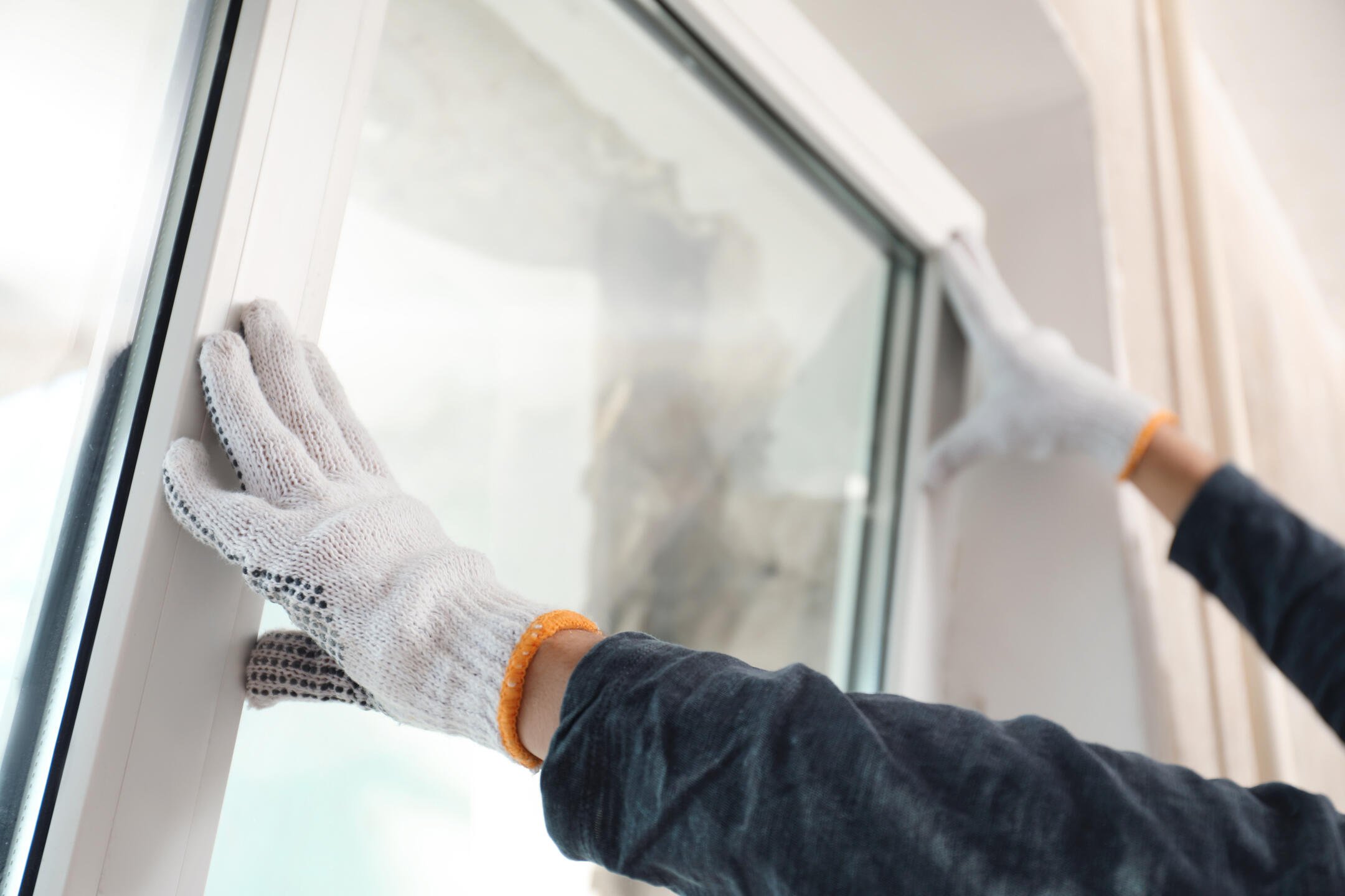 best replacement windows-close up of gloved hand installing new windows in home