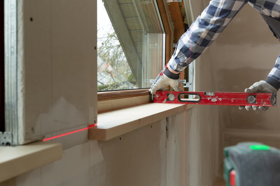 how to measure for replacement windows-man using a level to ensure new windows are installed correctly during construction