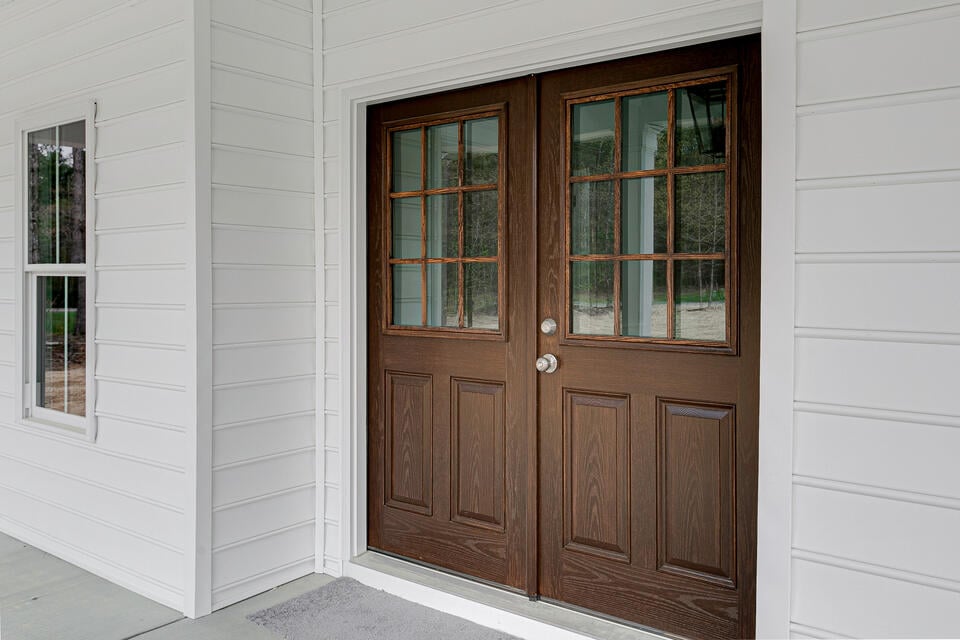 double front doors-dark wood front doors with silver hardware on white sided house