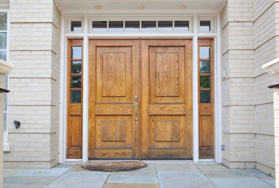 double front doors-wood front doors with gold hardware on white stone sided house