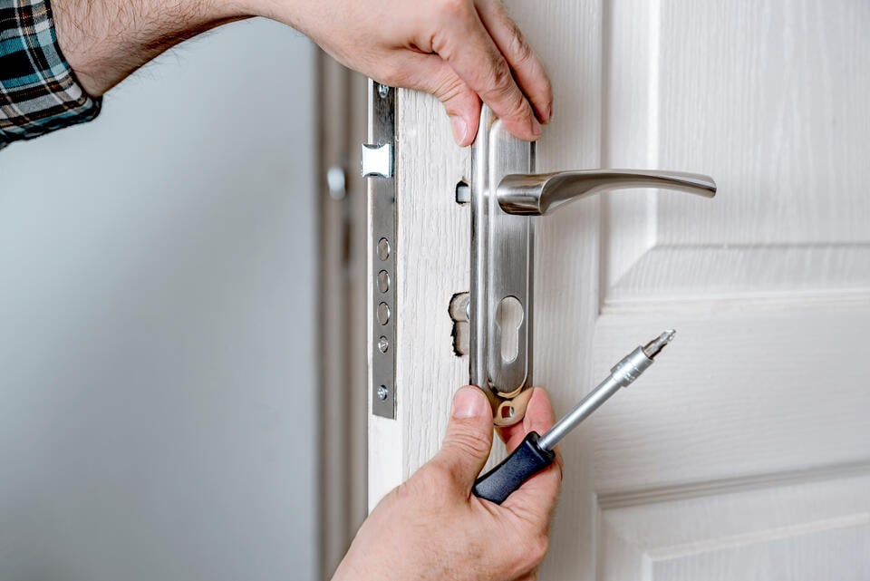 entry door installation-close up of someone installing hardware on front door
