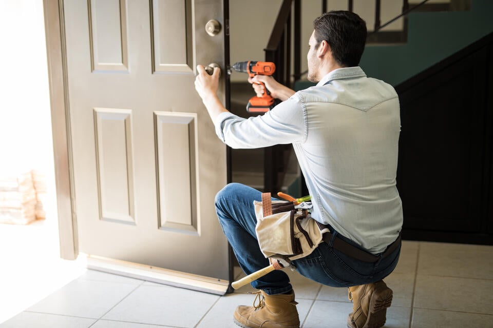 entry door installation-man using power tools to install finishes on a home front door
