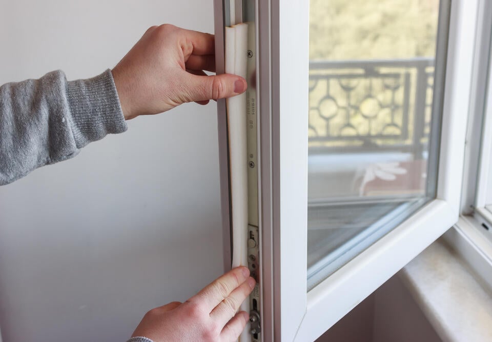 window seal repair-cose up of person measuring seal materials alongside window
