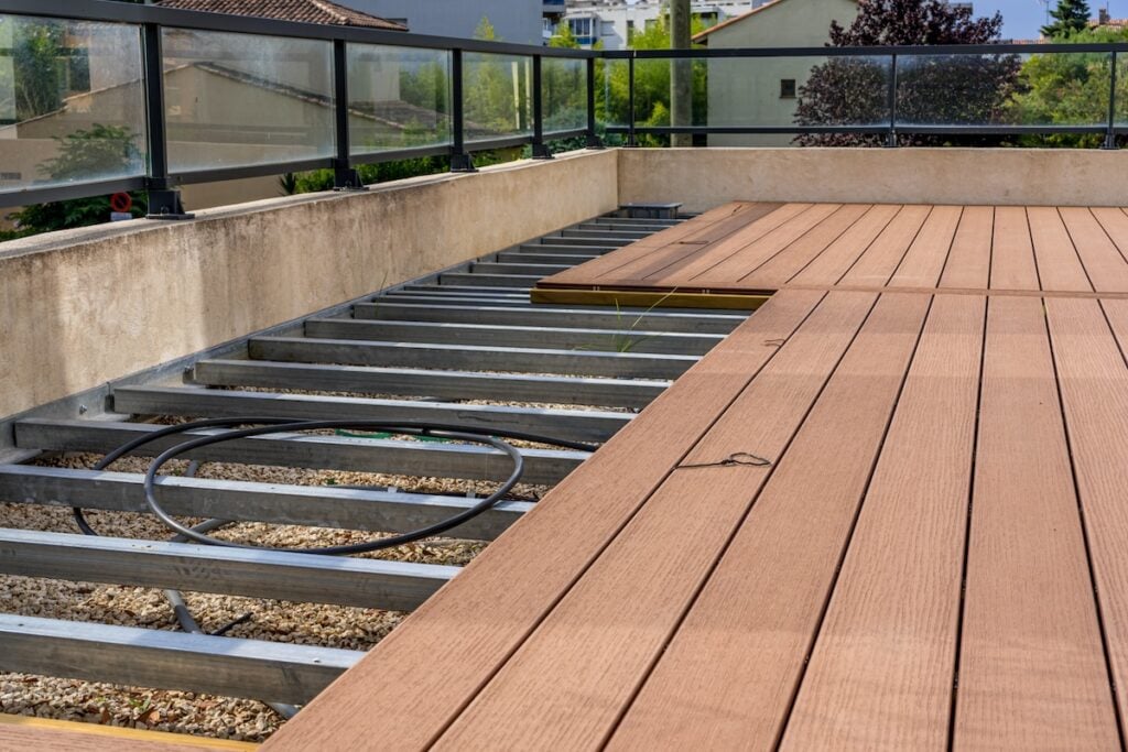 Construction of a wooden terrace on a balcony. A new wooden, timber deck being constructed. City background.