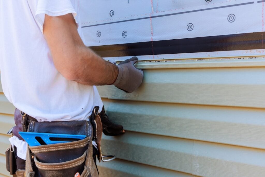 Construction worker installing new siding to a home