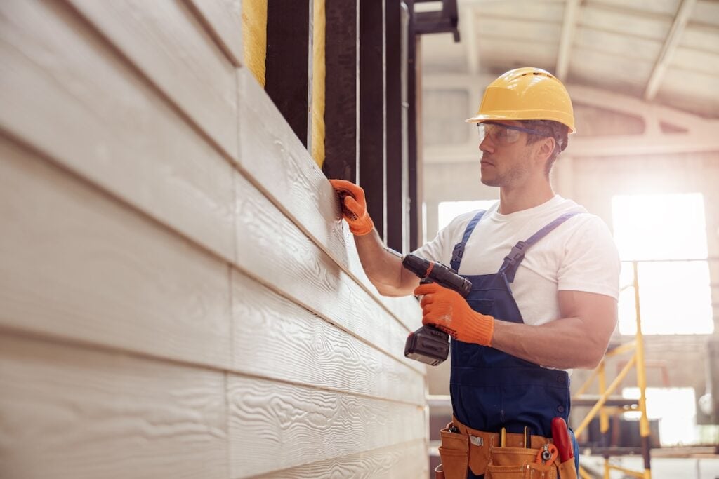 Worker practicing siding installation in company workshop