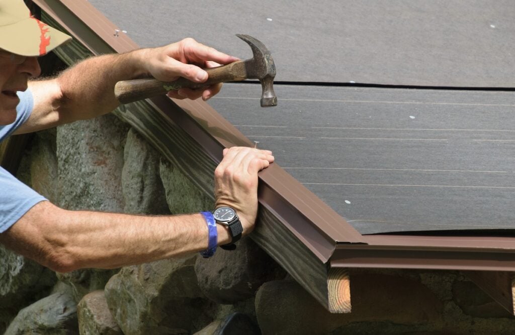Roofer installs metal drip edge flashing on roof
