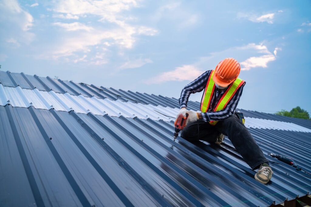 Professional roofer installing a metal roofing panel on structure