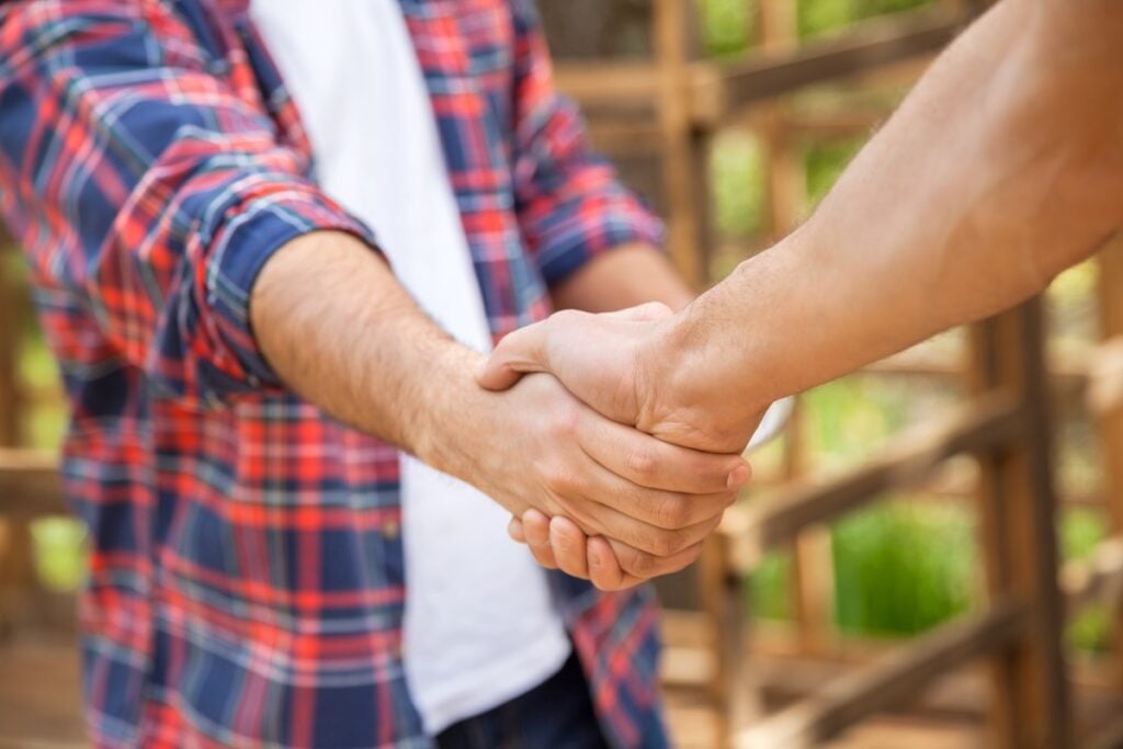 Cropped image of construction workers shaking hands in cabin at site