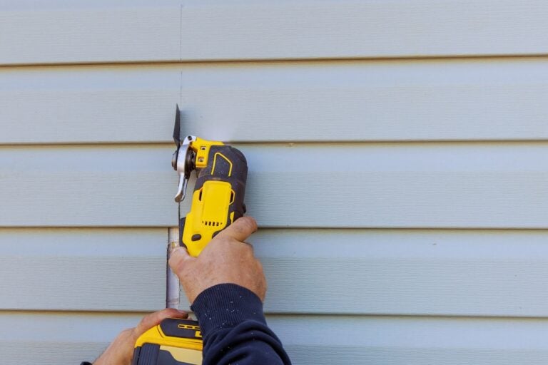 Reconstruction of house involves removal damaged vinyl siding with multi tool