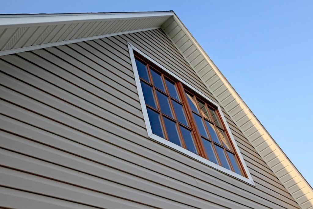 House rooftop and vinyl siding against a clear evening blue sky