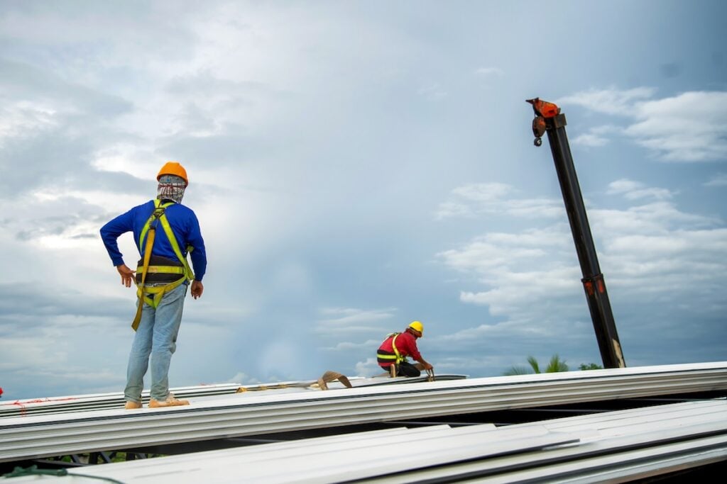 construction worker holding metal sheet installation tool to build industrial factory roof