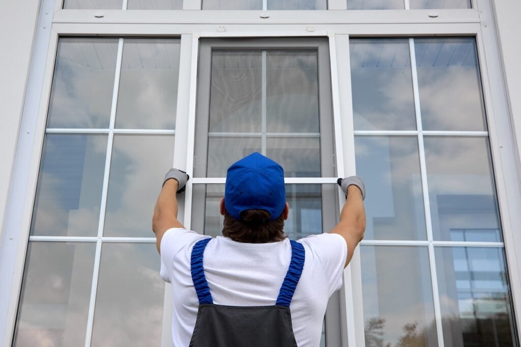 Professional craftsman outside the building installs a mosquito net on large window